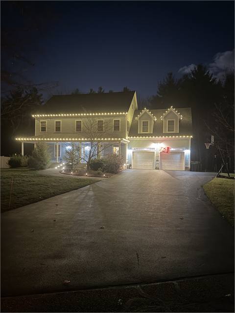 Large home with roofline lights and lit driveway