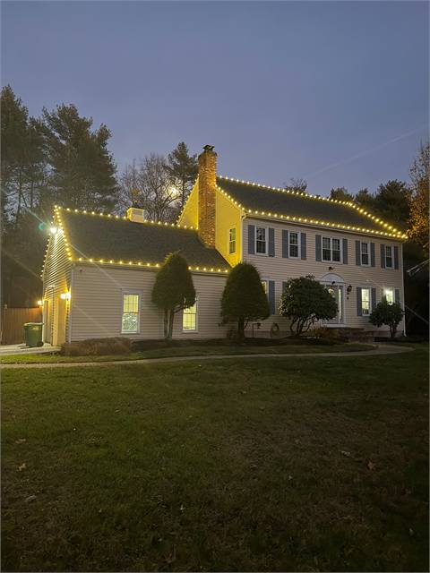 Colonial home lit with Christmas lights at dusk