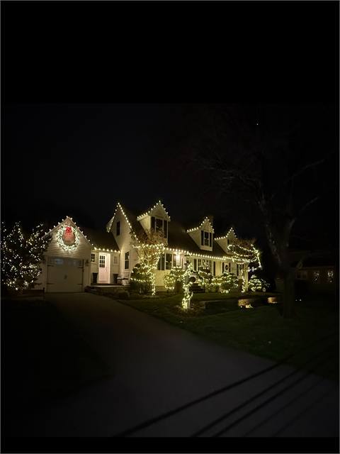 Cape-style home with lights and a lit wreath
