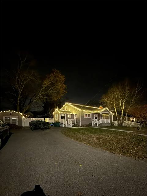 Ranch home with roofline lights and lit trees