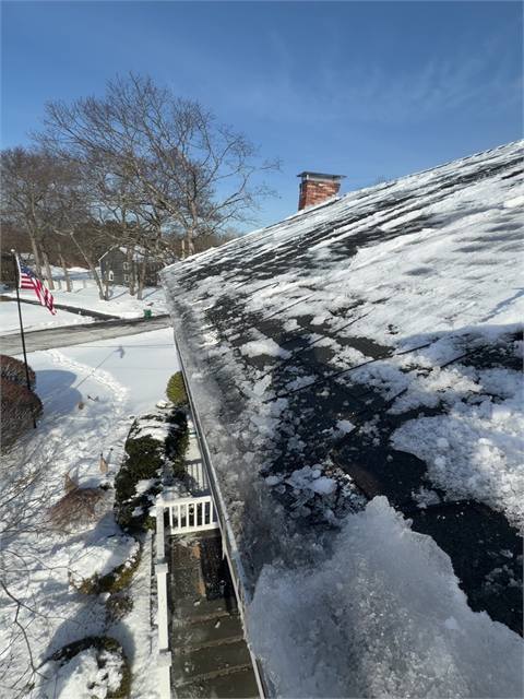 Snow-covered roof edge during ice dam removal