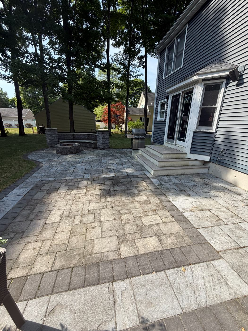 Paver patio with dark stains beside a blue house