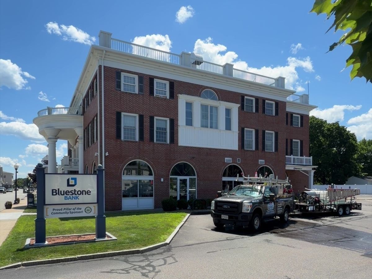 New England Pressure Pros truck and wash trailer at Bluestone Bank, a three-story brick commercial building